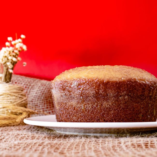 Moist homemade cake on a white plate with rustic burlap and red backdrop, perfect for food photography.